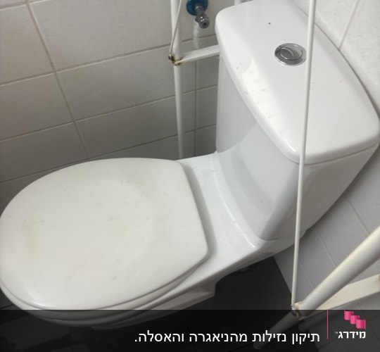 אסלה לבנה עם צינור מים בחדר אמבטיה